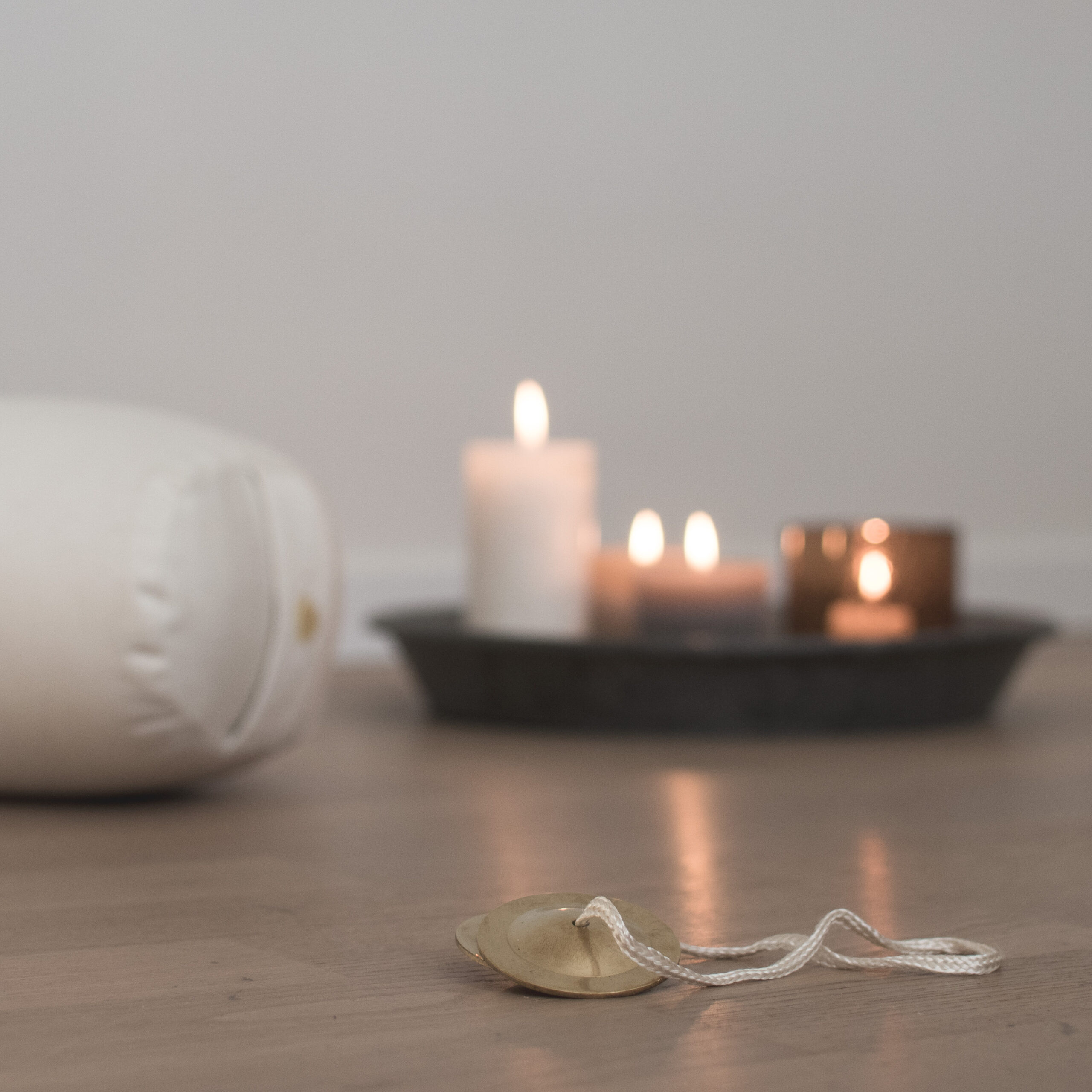 Anja Katharina Elmsheuser Mentoring Marburg Seelen-Alchemie – Heiliger Seminarraum für das Sommer-Retreat 2026 in Marburg Stadtmitte Nähe Bahnhof mit Tingsha-Zimbeln, weißem Meditations-Bolster und brennenden Kerzen auf hellem Holzfußboden für die absolute Erlösungs-Ruhe und Neuausrichtung

