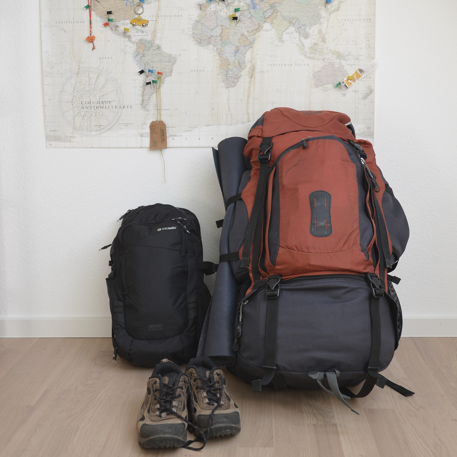 Anja Katharina Elmsheuser Mentoring Marburg Seelen-Alchemie: Ein Globetrotter Backpack Rucksack mit Wanderschuhen vor einer großen Weltkarte als Symbol für Stabilität, Erdung und das Fundament einer realen Heldenreise.